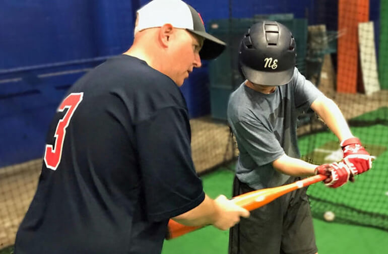 coach teaching a young player how to hit